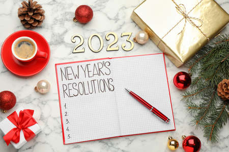Making resolutions for 2023 New Year. Flat lay composition with notebook and festive decor on white...