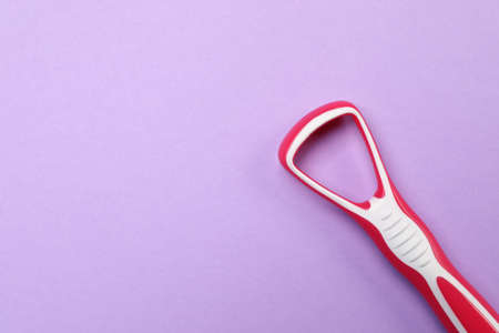 Red tongue cleaner on violet background, top view. Space for textの写真素材