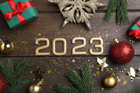 Flat lay composition with number 2023 and festive decor on wooden background. Happy new year