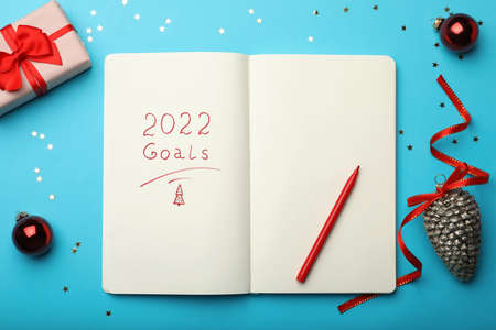 Open planner and Christmas decor on light blue background, flat lay. Planning for 2022 New Yearの写真素材