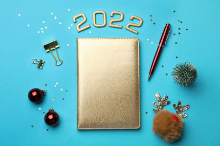 Golden planner and Christmas decor on light blue background, flat lay. Planning for 2022 New Yearの写真素材