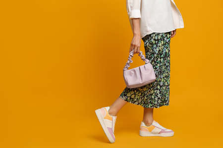 Stylish woman with trendy baguette bag on yellow background, closeup. Space for textの写真素材