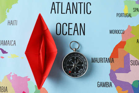 Red paper boat and compass on world map, flat layの写真素材