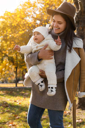 Happy mother with her baby daughter in park on sunny autumn day