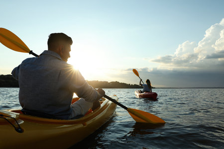 Couple kayaking on river at sunset, back view. Summer activityの写真素材