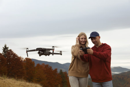 Young couple operating modern drone with remote control in mountainsの写真素材