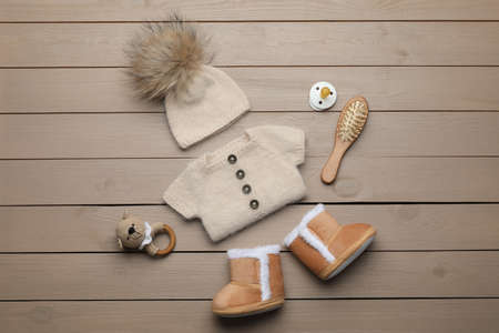 Flat lay composition with cute baby knitwear for photoshoot on wooden background