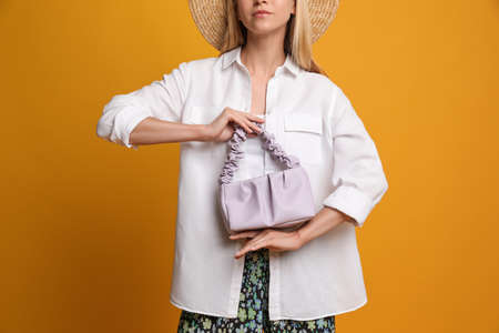 Stylish woman with trendy baguette bag on yellow background, closeupの写真素材