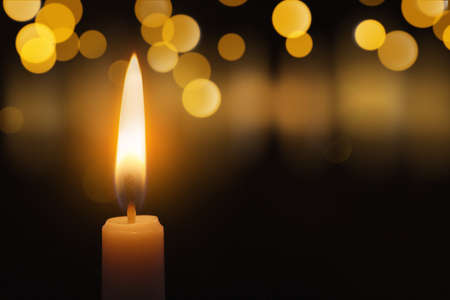 Wax candle burning in darkness, bokeh effect. Christmas eveの写真素材