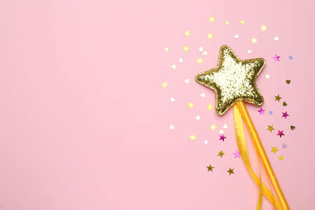 Beautiful golden magic wand and confetti on pink background, flat lay. Space for textの写真素材