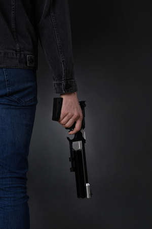 Gun shooting sport. Man holding standard pistol on dark background, closeupの写真素材
