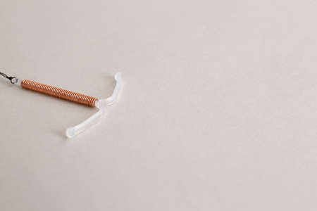 Copper intrauterine contraceptive device on light background. Space for textの写真素材