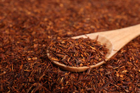 Heap of dry rooibos tea leaves with wooden spoon, closeup. Space for textの写真素材