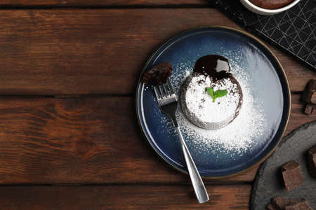 Delicious fresh fondant with hot chocolate and mint on wooden table, flat lay. Space for textの写真素材