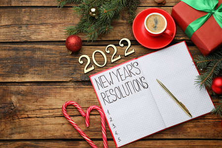 Making resolutions for 2022 New Year. Flat lay composition with notebook and festive decor on wooden...