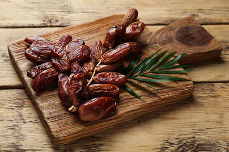Tasty sweet dried dates with green leaf on wooden table, closeupの写真素材