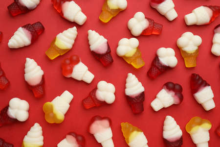 Tasty jelly candies in shape of ice cream on red background, flat layの写真素材