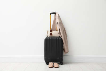 Suitcase packed for trip, shoes, jacket and accessories near white wall indoorsの写真素材