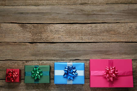 Many colorful gift boxes on wooden table, flat lay. Space for text