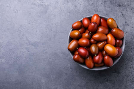 Ripe red dates in bowl on gray table, top view. Space for textの写真素材