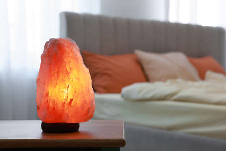 Himalayan salt lamp on wooden table in bedroom, space for textの写真素材