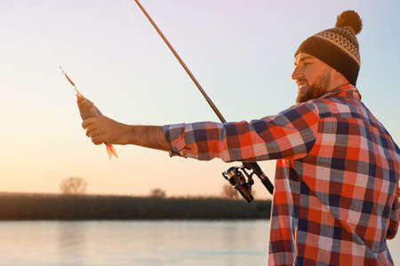 Fisherman with rod and caught fish at riversideの写真素材
