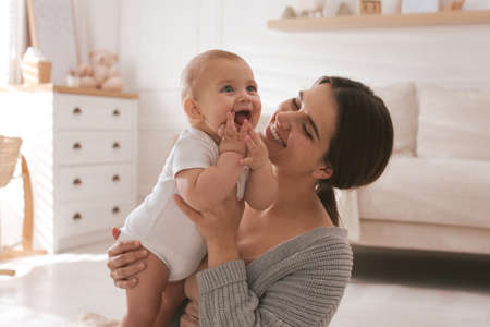Happy young mother with her cute baby at homeの写真素材