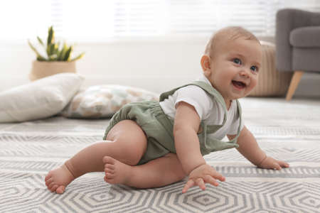 Cute baby crawling on floor at home