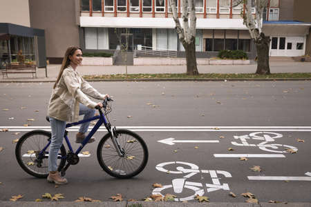 Happy beautiful woman with bicycle on lane in cityの写真素材
