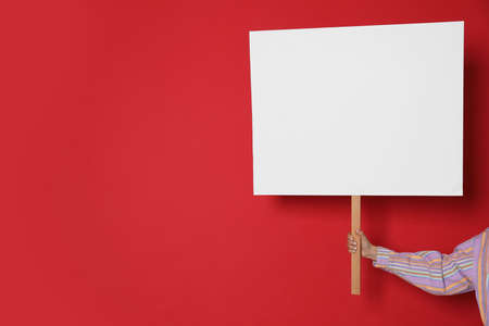 Woman holding blank sign on red background, closeup. Space for textの写真素材