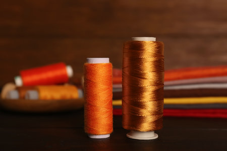 Different color sewing threads on black wooden table