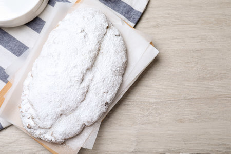 Delicious Stollen sprinkled with powdered sugar on wooden table, top view. Space for textの写真素材
