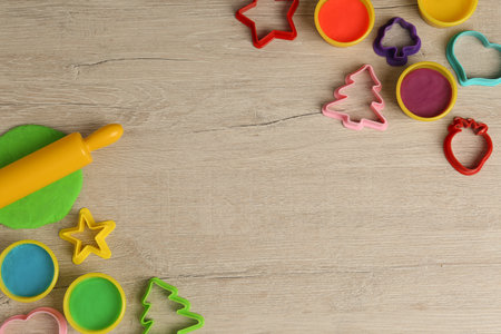 Different color play dough and tools on wooden table, flat lay. Space for textの写真素材