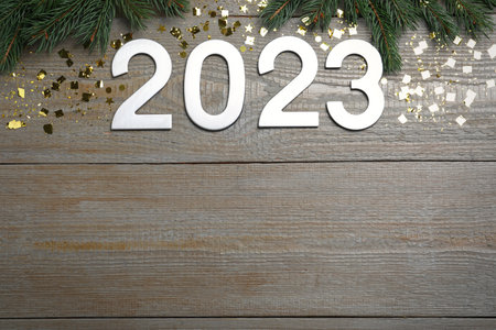 Flat lay composition with number 2023 and festive decor on wooden background, space for text. Happy...