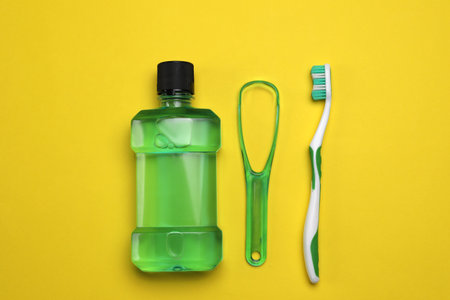 Tongue cleaner, mouthwash and toothbrush on yellow background, flat layの写真素材