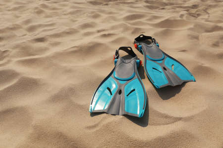Pair of turquoise flippers on sand. Space for textの写真素材