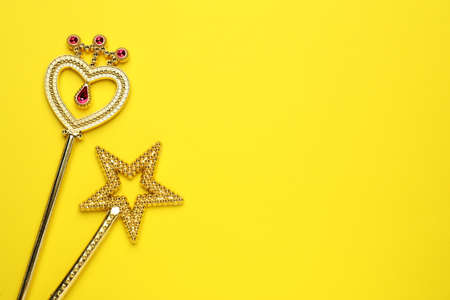 Beautiful golden magic wands on yellow background, flat lay. Space for textの写真素材