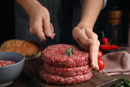 Woman making raw hamburger patty at wooden table, closeupの写真素材