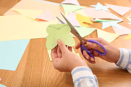 Woman cutting color paper with scissors at wooden table, closeupの写真素材