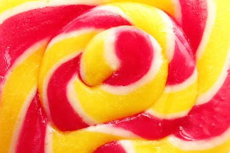 Sweet colorful lollipop on pink background, closeup view. Delicious candy