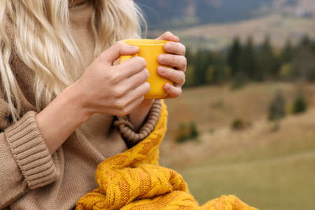 Young woman with mug of hot drink outdoors, closeup. Space for textの写真素材