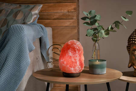 Beautiful Himalayan salt lamp, eucalyptus branches and candle on wooden table in living roomの写真素材