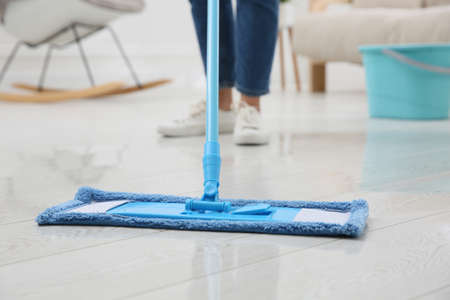 Woman cleaning parquet floor with mop at home, closeup