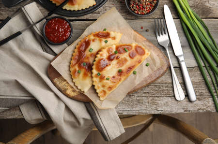 Delicious fried chebureki with ketchup served on wooden table, flat layの写真素材