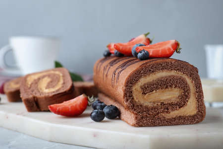 Tasty chocolate cake roll with cream and berries on board, closeupの写真素材