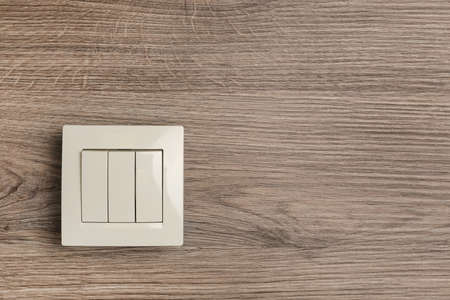 White light switch on wooden background. Space for text