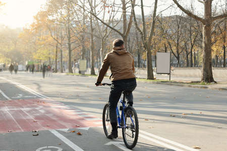 Man riding bicycle on lane in city, back viewの写真素材