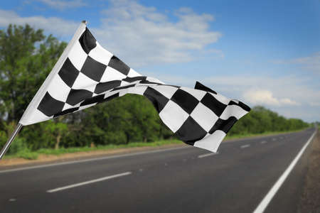 Checkered racing finish flag and asphalt road outdoorsの写真素材