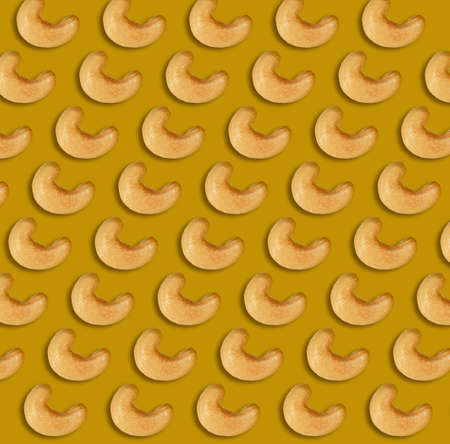 Many tasty cashew nuts on brownish-yellow background, flat lay