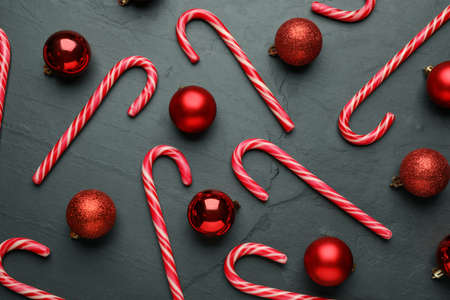 Tasty candy canes and Christmas balls on black table, flat layの写真素材